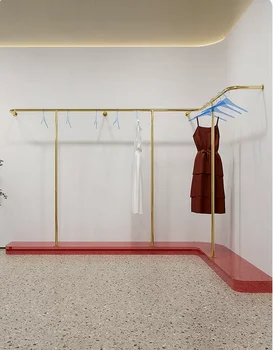 Изготовленный на заказ стеллаж для выставки женской одежды из нержавеющей стали с золотой подвесной вешалкой для одежды на стене стеллажа для выставки товаров в магазине одежды